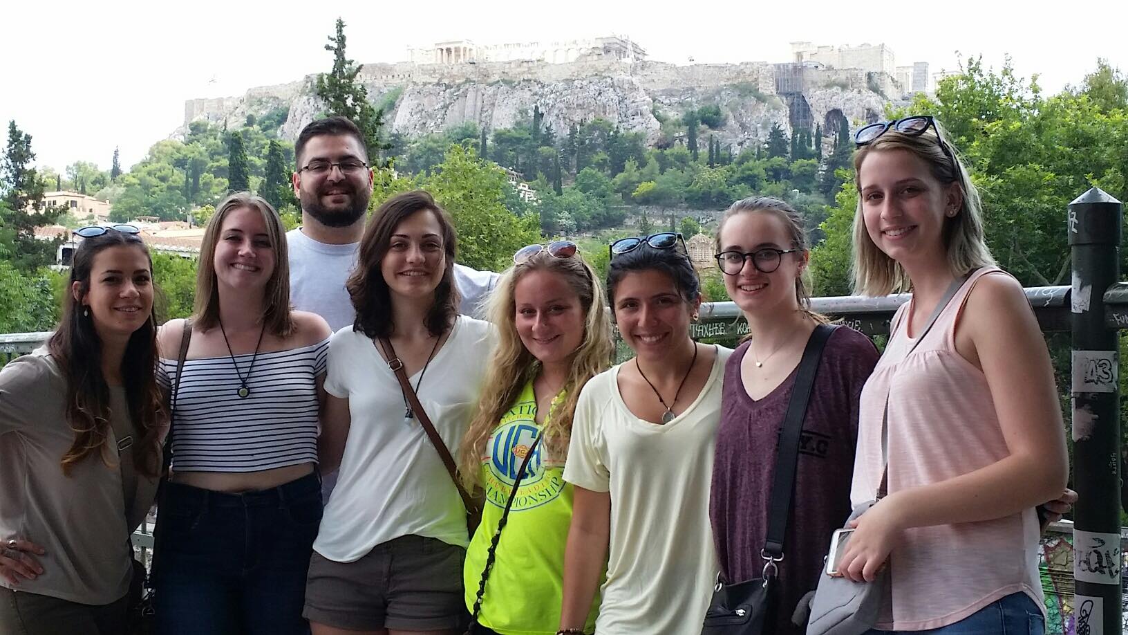 group of students pose before the Athenian Acropolis--in the distance