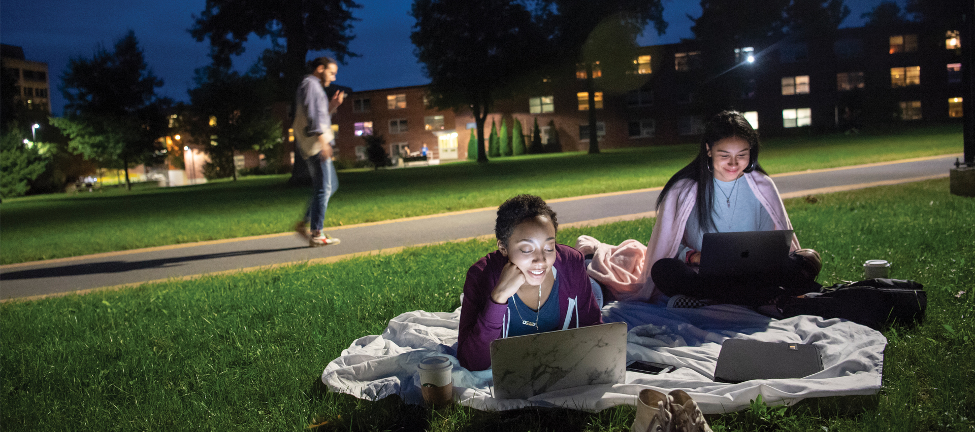 students sitting on the grass under a night sky
